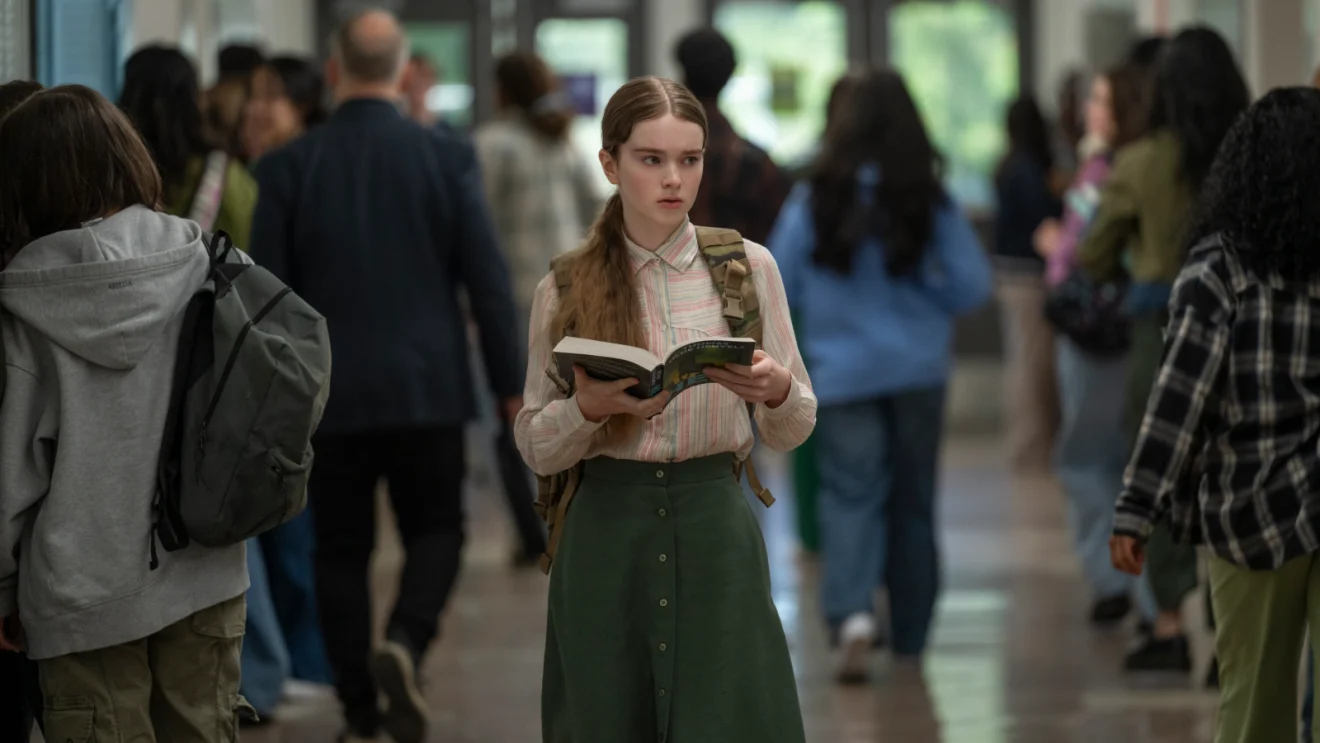 Summer H. Howell como Carrie White, segurando um livro no corredor da escola.