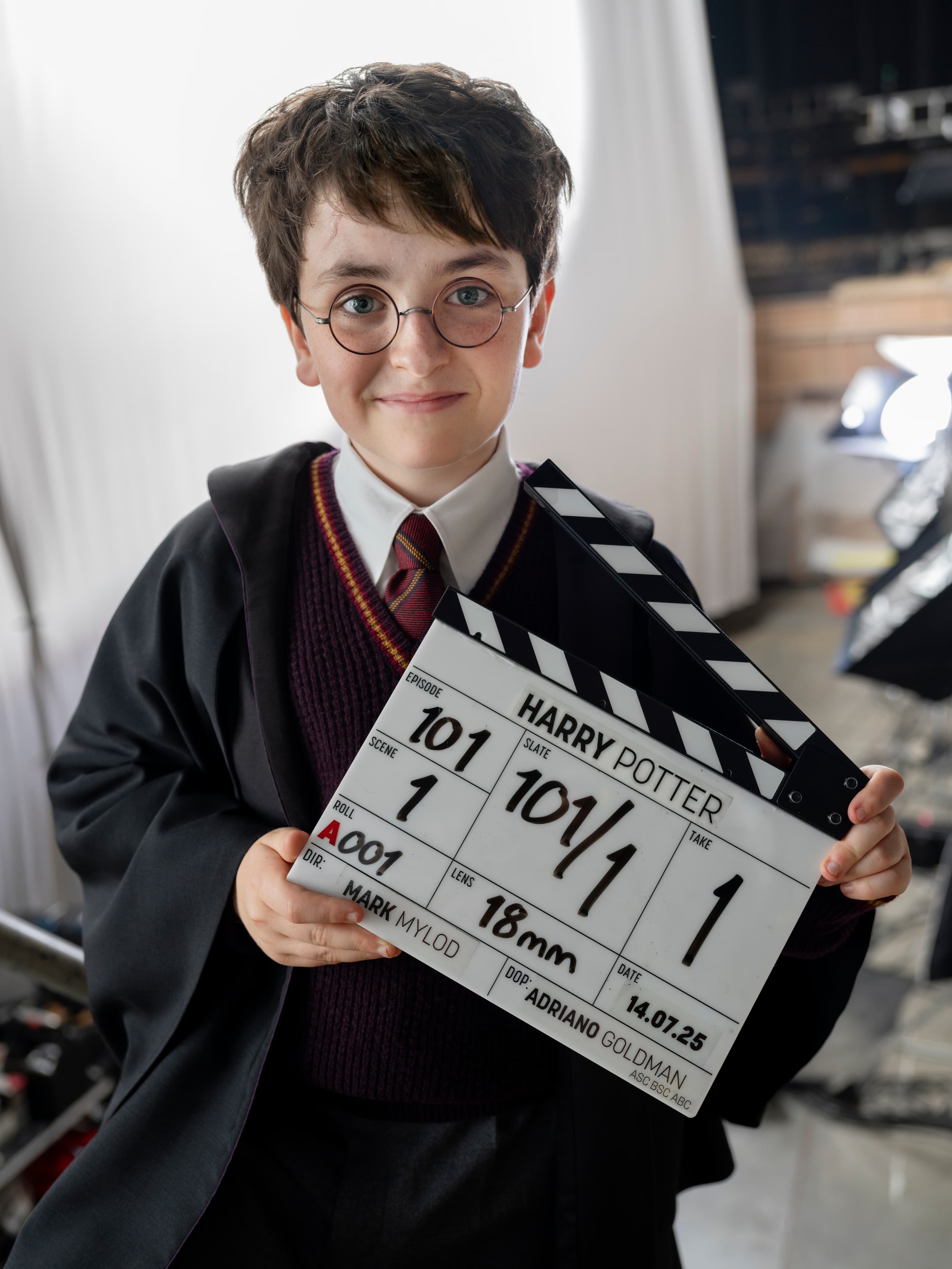 Dominic McLaughlin como Harry Potter, segurando a claquete da série nos bastidores.